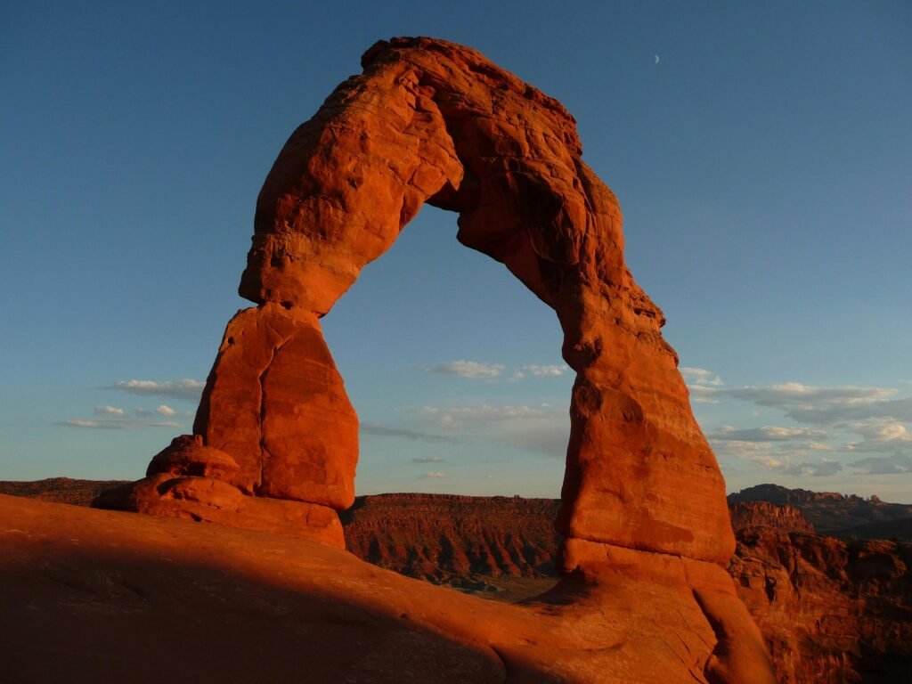 Capture of the iconic Delicate Arch in Utah's Arches National Park during sunset showcasing its stunning red hues.