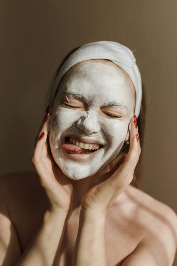 Happy woman with a clay mask, smiling and enjoying her skincare routine. Perfect for wellness and beauty themes.