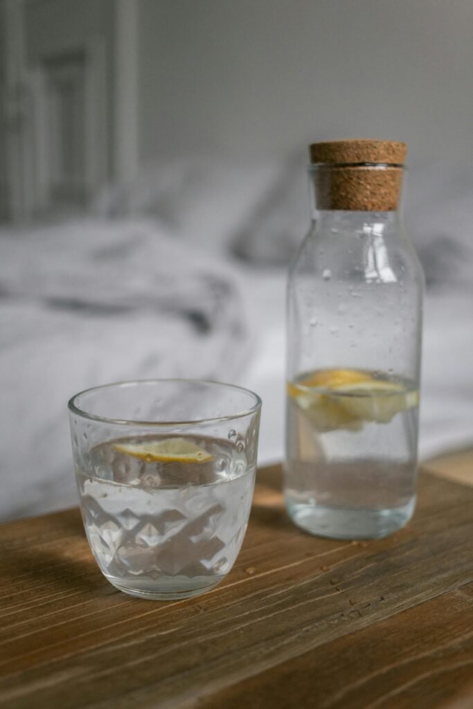 Close-up of a glass and bottle with lemon water on a wooden surface, perfect for health and lifestyle concepts.