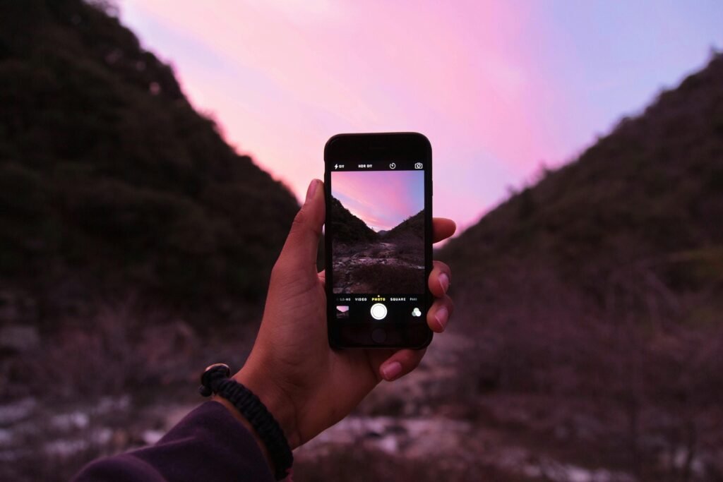 A person photographs a stunning sunset landscape with a smartphone in nature.