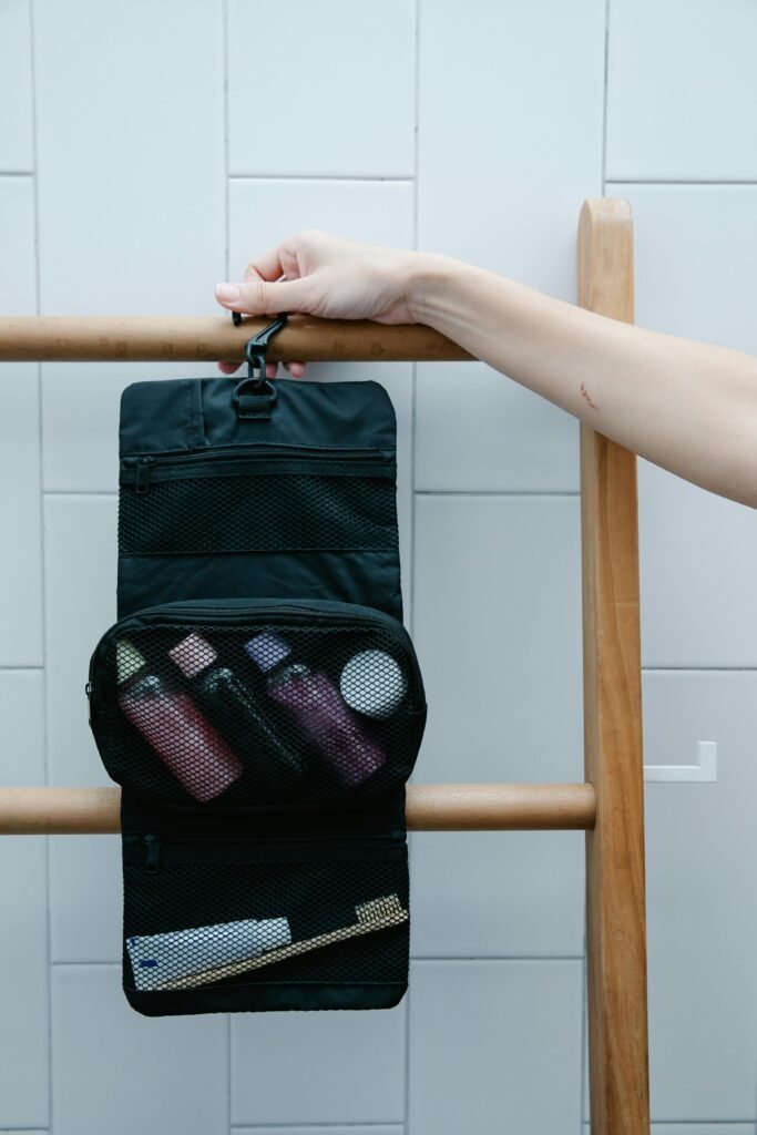 Close-up of a toiletry bag hanging on a wooden rack with toiletries.