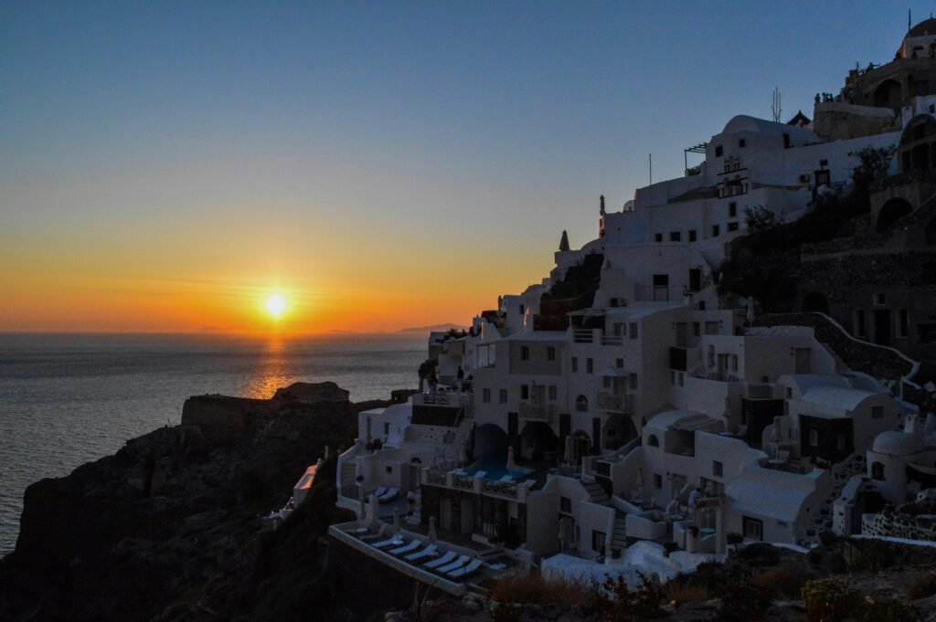 Stunning view of Santorini's white clifftop houses against a vibrant sunset over the sea.