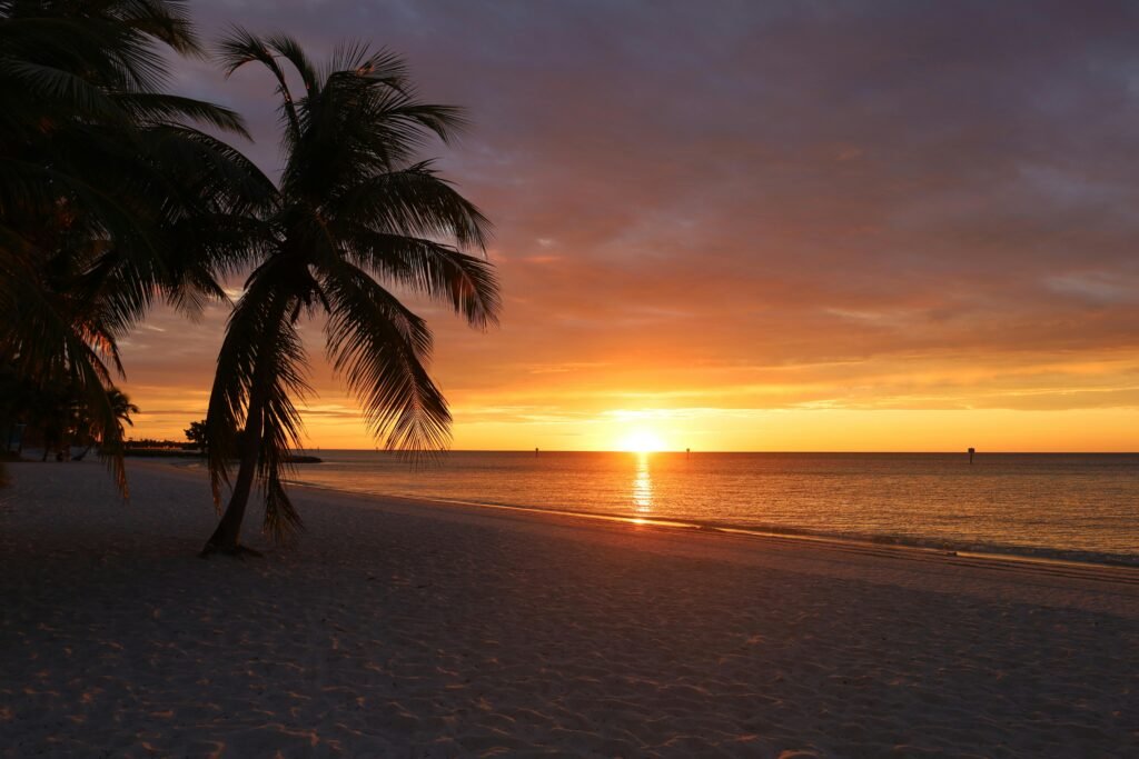 Experience a breathtaking sunset over the tranquil sea at a sandy beach in Key West.