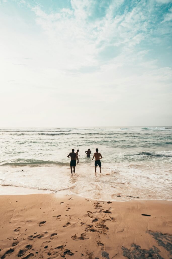 Three friends run into the ocean on a sunny day at a scenic beach in Bali.