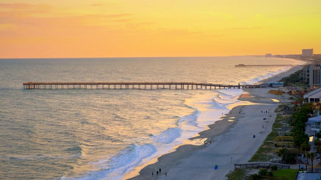 Stunning aerial view of Myrtle Beach, SC at sunset with pier extending into the ocean.