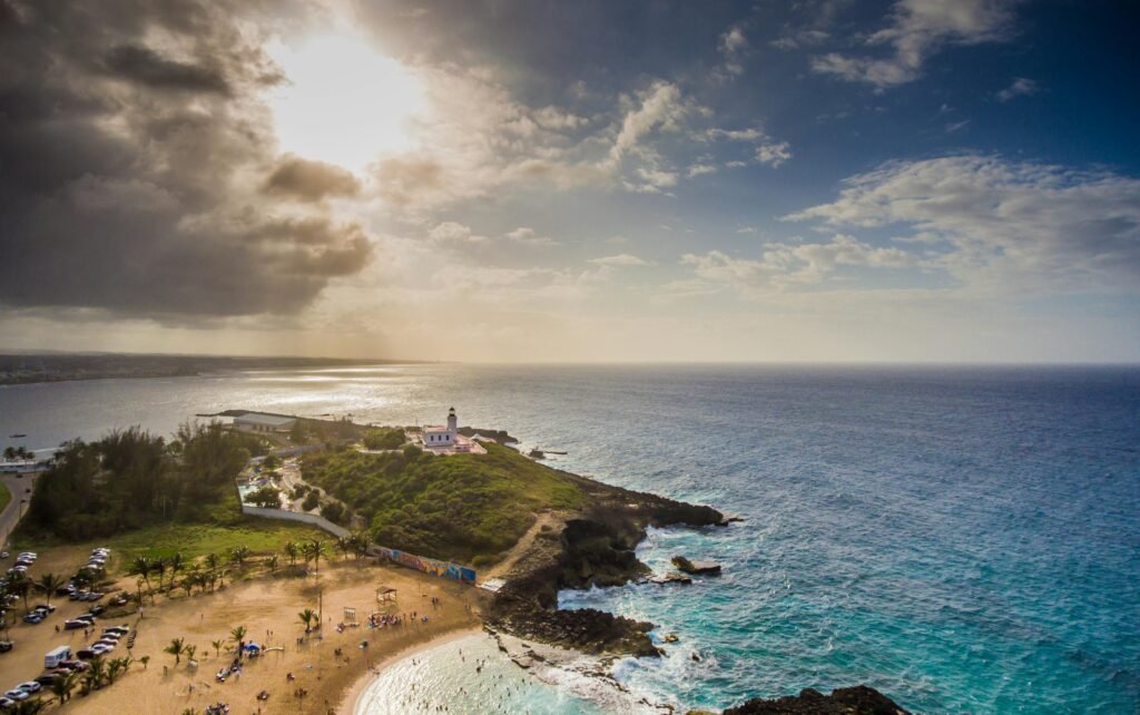 Stunning aerial shot of the Rincón lighthouse overlooking a tropical beach and the Atlantic Ocean in Puerto Rico.