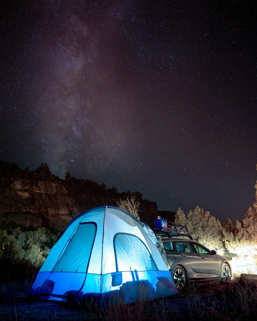 Starry night at a campground with a tent and car in Springdale, Utah.