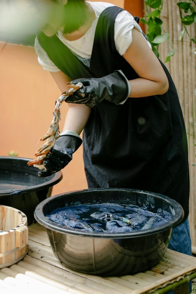 A woman skillfully demonstrates traditional shibori tie-dye technique in an outdoor setting.